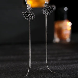 Pair of silver earrings with leaf designs on a dark background