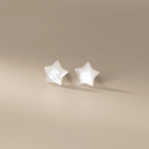 Star-shaped earrings on a beige background