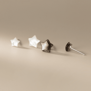 Four star-shaped earrings on a beige background