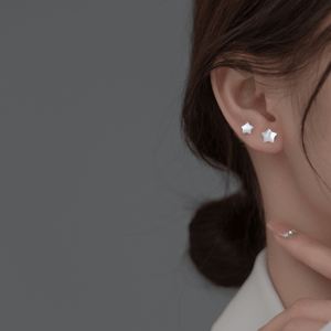 Star-shaped earrings worn by a person with a neutral background