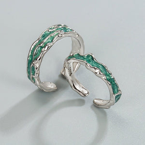 Silver toe rings with green gemstone inlay on a light gray background