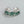 A pair of silver rings with green accents, designed to be adjustable and fit US sizes. The rings have a textured finish and are presented against a light background.