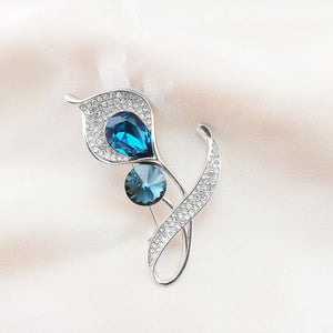 Silver brooch with blue gemstones on a light background