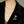 Black jacket with a decorative brooch featuring blue gemstones on a neutral background