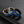 Three rings with blue and gold designs on a black textured surface