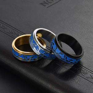 Three rings with blue and gold designs on a black textured surface