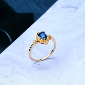 Gold ring with a blue gemstone on a light blue background