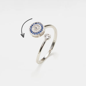 Silver evil eye spinner ring with blue gemstones on a white background