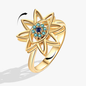 Gold evil eye flower spinner ring with a blue gemstone on a white background