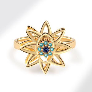 Gold evil eye flower spinner ring with a blue gemstone on a white background