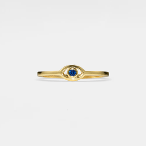 Gold evil eye ring with a blue gemstone on a light gray background