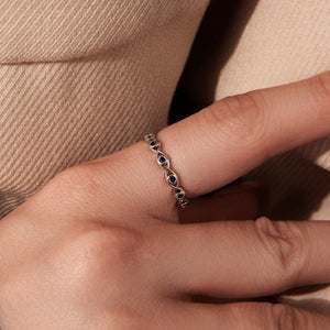 Model wearing a evil eye ring with blue gemstones on a light gray background