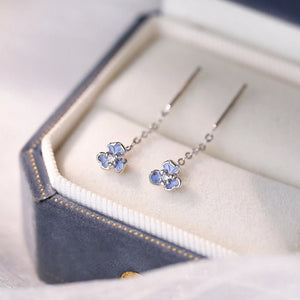 Flower-shaped earrings in a hexagonal jewelry box on a light background