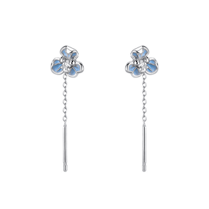 Pair of floral earrings with blue petals and clear gemstones on a white background