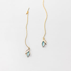 Gold leaf-shaped earrings on a light gray background