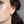 Close-up of a person wearing a gold hoop earring with a neutral background