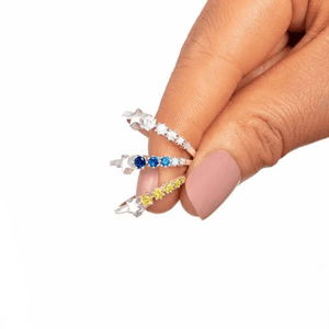 Hand holding three star-shaped rings with gemstones on a white background