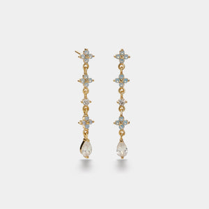 Gold earrings with gemstones on a light gray background