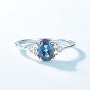 Silver ring with a blue gemstone and small diamonds on a light blue background