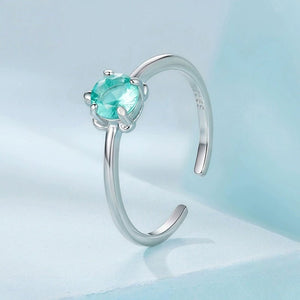 Silver sea turtle ring with a blue gemstone on a light blue background