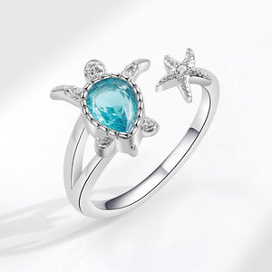 Silver sea turtle ring with a blue gemstone and starfish design on a white background