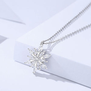 A silver snowflake pendant necklace with blue cubic zirconia stones, displayed against a white background.