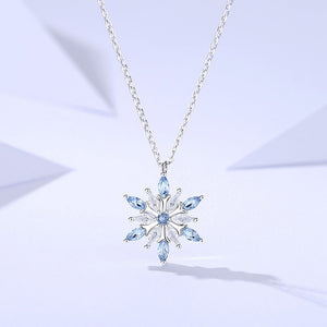 Snowflake-shaped pendant necklace with blue gemstones on a light purple background