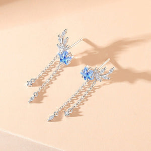 Elegant silver earrings with blue gemstones on a beige background