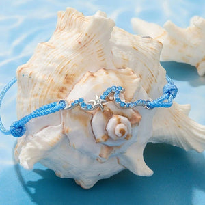 Blue cord bracelet on a large shell with a blue background