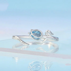Silver ring with a pear-shaped blue gemstone on a light blue background