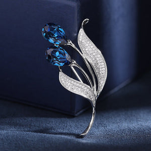 Silver brooch with blue gemstones on a dark blue background