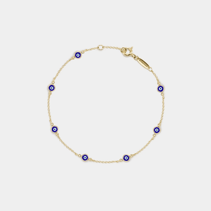 Gold bracelet with blue evil eye charms on a light gray background