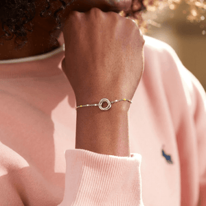 Person wearing a bracelet with a pink sweater