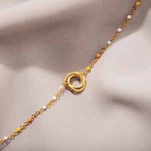 Gold bracelet with interlocking rings on a beige fabric background