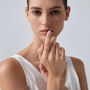 Woman wearing a silver ring on her finger against a plain background