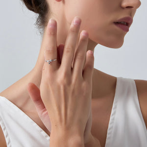 Close-up of a woman's hand wearing a silver ring on a neutral background