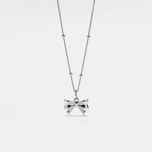 A gold-plated sterling silver bow tie charm on a chain, against a white background.