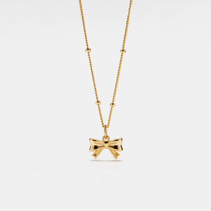 Gold bow-shaped pendant on a chain against a white background