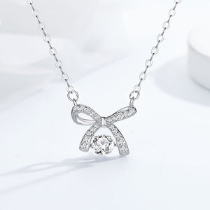 Silver bow-shaped necklace with a clear gemstone on a light gray background