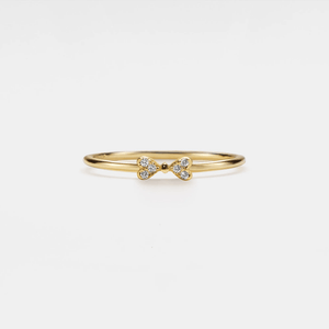Gold ring with bow design on a light gray background