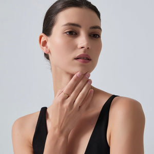 Woman wearing a gold ring on her finger against a plain background