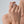 Close-up of a hand wearing a gold ring on a neutral background
