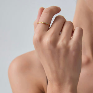 Close-up of a hand wearing a gold ring on a neutral background