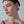 Close-up of a woman wearing a delicate earring against a neutral background