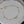 Gold bracelet with star and bow charms on a light gray plate