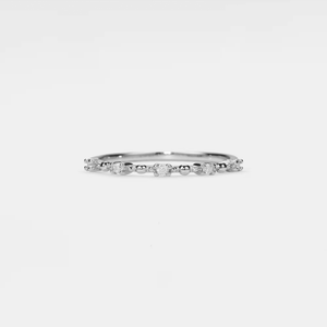 Silver ring with small diamonds on a light gray background