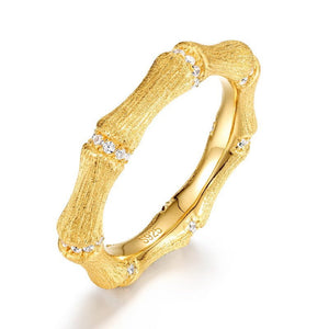 Gold ring with textured design and small diamonds on a white background