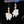 Pair of floral earrings with gold accents and clear gemstones on a dark background