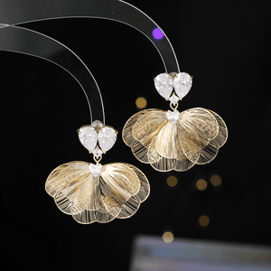 Gold butterfly earrings with clear gemstones on a dark background