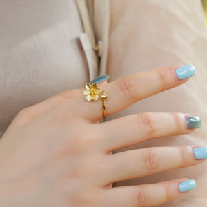 Gold flower ring on a finger with light blue nail polish